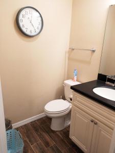 a bathroom with a toilet and a clock on the wall at Private Entrance 1 Bd Guest Suite in Cypress Gardens near Legoland in Winter Haven