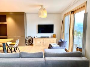 a living room with a couch and a flat screen tv at Petit Tannenboden - CharmingStay in Flumserberg