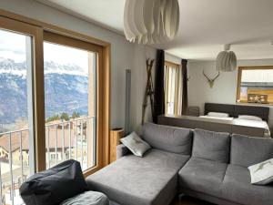 a living room with a couch and a bed and a window at Petit Tannenboden - CharmingStay in Flumserberg
