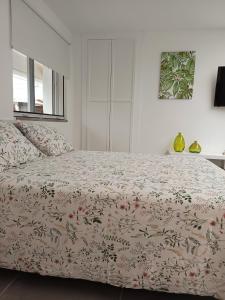 ein Schlafzimmer mit einem Bett mit geblümter Tagesdecke in der Unterkunft Mini Casa cerca del Mar in Punta del Hidalgo