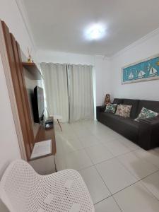 a living room with a couch and a tv at 201- Apartamento Bombas com vista lateral do mar in Bombas