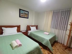 pokój hotelowy z 2 łóżkami i zieloną pościelą w obiekcie Close to Airport - Free One Time Pickup - A y J Familia w mieście Lima