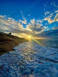 a sunset on a beach with the ocean at Vila flores e mar in São Miguel do Gostoso