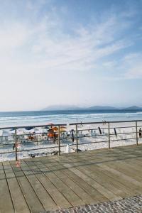 a boardwalk on the beach with people in the water at Casa confortável a 5 minutos da Praia do Forte a pé in Cabo Frio