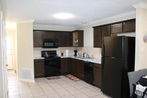 a kitchen with wooden cabinets and a black refrigerator at Lubbock haven Rooms with individual Bathrooms in Lubbock +26 photos
