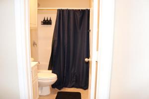 a bathroom with a toilet and a black shower curtain at Lubbock haven Rooms with individual Bathrooms in Lubbock
