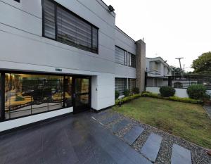 a white building with large windows and a yard at Apartamento Flor de Azúcar - Casa Tartaruga Bogotá in Bogotá