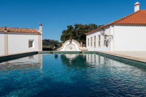 a swimming pool in front of two white buildings at Cazal d'Oliveira in Granja