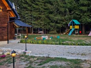 a park with a playground and a house with lights at Vacation Home Miki 2 in Ljuboš