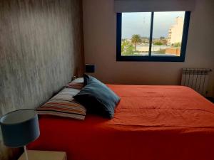 1 dormitorio con 1 cama con manta naranja y ventana en Apartamento en el centro de la ciudad, en Villa María