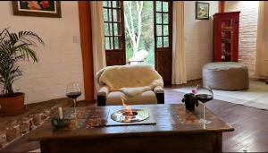 a living room with a table and two glasses of wine at CHALÉ AZALÉA Lindo chalé NO CAMPO com roupas de cama e banho impecáveis, Wi-Fi StarLink de alta velocidade, cozinha equipada, estacionamento privativo, decks, jardins, lareiras, conforto, privacidade e belíssimas paisagens in Cunha