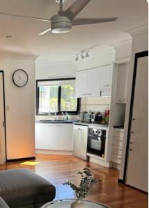 a kitchen with white cabinets and a clock on the wall at Stylish & Elegant 2BR Townhouse in Wilston, Brisbane in Brisbane