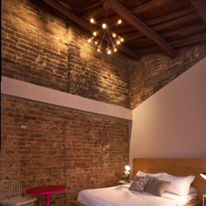 una camera da letto con un muro di mattoni, un letto e un lampadario a braccio di Alojamiento en el corazon de Teusaquillo a Bogotá