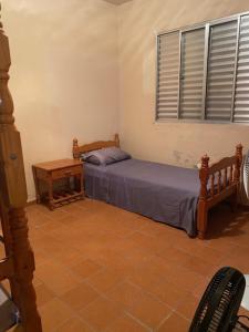 a bedroom with a bed and a table and a window at Apartamento Itaguá in Ubatuba