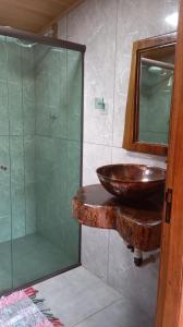 ein Badezimmer mit Waschbecken und Glasdusche in der Unterkunft Pousada Rural e Pesqueiro Chalé da serra in Conceição da Ibitipoca