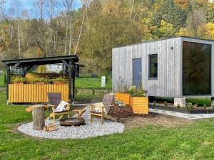 a small shed with chairs and a table in the grass at Tiny house u řeky - Bouda Krušnohorka in Vojkovice