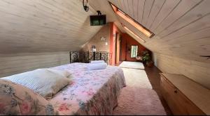 a bedroom with a bed in a attic at CHALÉ AZALÉA Lindo chalé NO CAMPO com roupas de cama e banho impecáveis, Wi-Fi StarLink de alta velocidade, cozinha equipada, estacionamento privativo, decks, jardins, lareiras, conforto, privacidade e belíssimas paisagens in Cunha