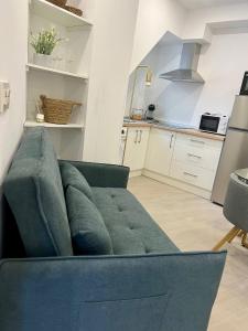 a blue couch in a living room with a kitchen at Apartamento Turístico Centro Antequera B in Antequera