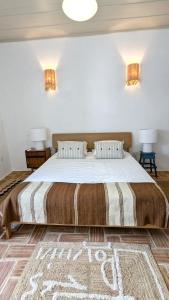 a bedroom with a large bed with two lamps at Casa Caiada in Beja