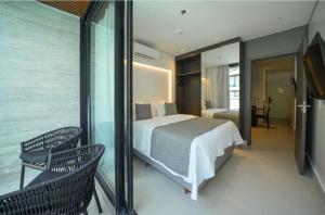 a bedroom with a bed and a balcony with two chairs at Porto Alto Resort Muro Alto B02-215 - 224 in Ipojuca +50 photos