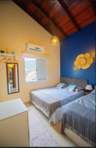 deux lits dans une chambre aux murs bleus dans l'établissement Linda casa em Juquehy a 150 metros da praia!! Casa em condomínio!, à São Sebastião 16 autres photos