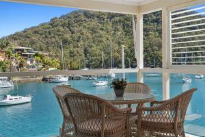 a porch with a table and chairs and boats in the water at The Cove Church Point in Church Point +1 photo