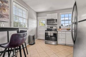 a kitchen with a refrigerator and some chairs in it at East Hill Retreat Near Beaches & Downtown in Pensacola +16 photos