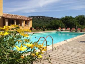 una piscina con terraza de madera junto a una casa en La Grande Bouisse, en Céreste