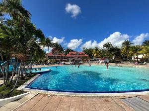 a large swimming pool with people in a resort at studio La Cocoteraie, vue mer in Courcelles Sucrerie