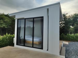 a bedroom in a house with large windows at De'La Moon เดอ ลา มูน in Ban Klaeng Bon