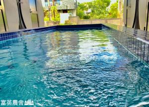 a swimming pool with blue water in a building at Fuying Farmhouse in Dongshan