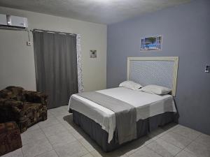 um quarto com uma cama e uma cadeira em Modern apt at West village em Montego Bay