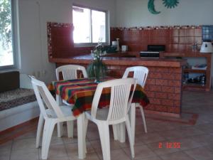 a dining room table with four white chairs and a kitchen at BONITO APARTAMENTO RODEADO DE PALMERAS primer nivel in Barra de Navidad
