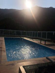 a large swimming pool with the sun in the background at Apartamento aconchegante na Praia in Ubatuba