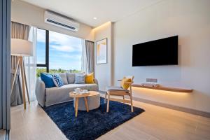 un salon avec un canapé et une télévision sur un mur dans l'établissement Laguna Lakeside Residences by Banyan Living, à Laguna Phuket
