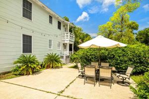 a patio with a table with an umbrella and chairs at East Hill Manor with 2 Kitchens Near Beach & Downtwn in Pensacola