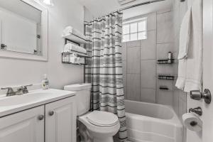 a white bathroom with a toilet and a sink at East Hill Manor with 2 Kitchens Near Beach & Downtwn in Pensacola +34 photos