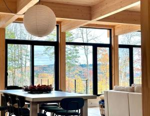a dining room with a table and chairs and windows at La Kabina with Mt Tremblant view in La Conception