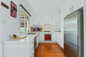 cocina blanca con armarios blancos y nevera en Jado on the Lake, Jervis Bay, en St Georges Basin