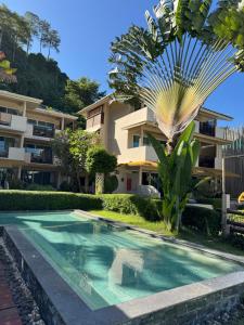a palm tree and a swimming pool in front of a building at Mama Beach Residence - Adults Only in Phi Phi Islands