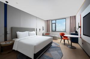 ein Hotelzimmer mit einem weißen Bett und einem Schreibtisch in der Unterkunft Holiday Inn Express Zhengzhou Nongye Road by IHG in Zhengzhou