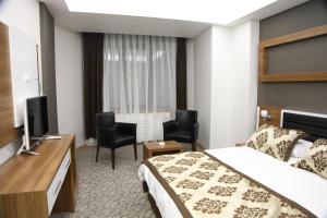 ein Hotelzimmer mit einem Bett und einem Flachbild-TV in der Unterkunft Afyon Grand Ari Hotel in Afyonkarahisar