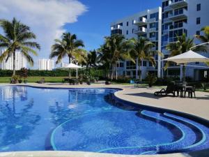 a swimming pool with palm trees and a building at Alojamiento Vacacional de Playa in Río Hato