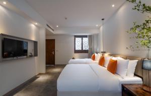 a bedroom with a large white bed and a flat screen tv at Mount Emei Heyuan Serene Residence Hot Spring Hotel in Emeishan City
