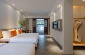a hotel room with two beds and a television at Mount Emei Heyuan Serene Residence Hot Spring Hotel in Emeishan City