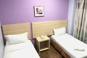 two beds in a room with purple walls at YP Boutique Hotel, Paradigm Mall Petaling Jaya in Petaling Jaya