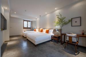 a bedroom with two beds and a table and a desk at Mount Emei Heyuan Serene Residence Hot Spring Hotel in Emeishan City