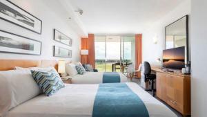 a hotel room with two beds and a desk at Lovely Studio Apartment Overlooking Golf Course! in Pelican Waters