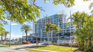 a tall building with palm trees in front of it at Lovely Studio Apartment Overlooking Golf Course! in Pelican Waters