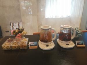 twee koffiezetapparaten en een dienblad met gebak op tafel bij Echarm Hotel Wuzhou Canghai Lake High Speed Railway Station in Wuzhou